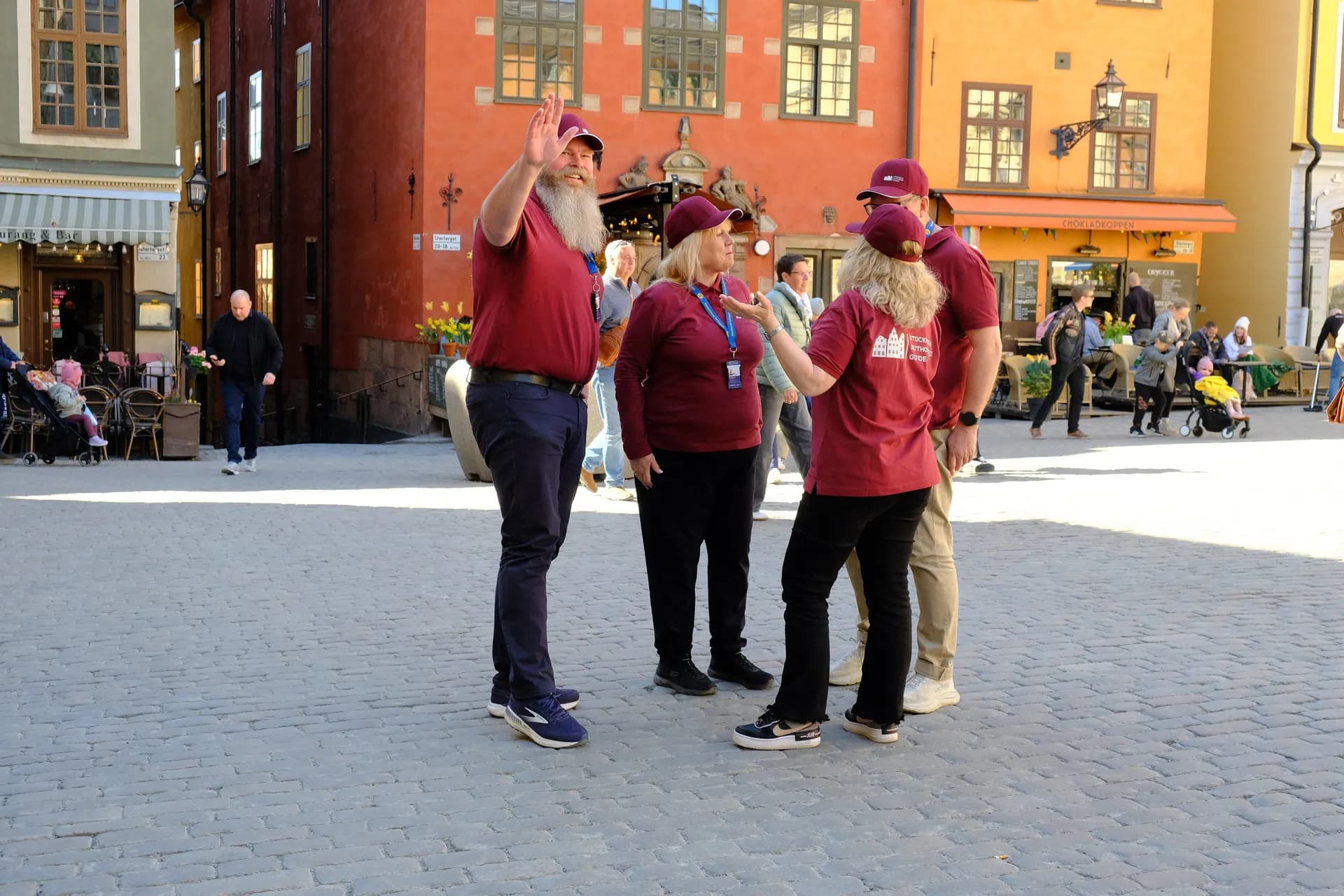 Six people with name tags are standing outdoors, with buildings and water in the background